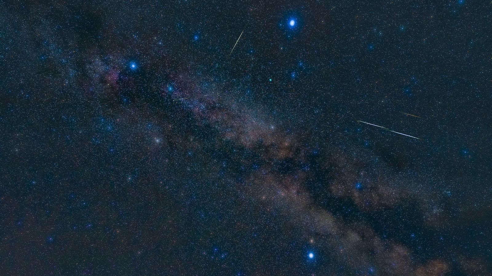 night sky image showing three bright stars forming a triangle, with the milky way glowing between.