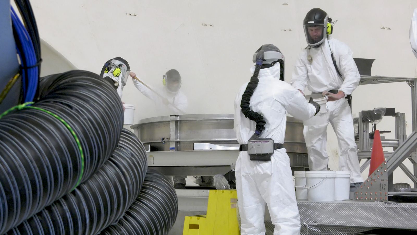A crew loads simulated lunar dirt into the test bin in the 60' vacuum sphere.