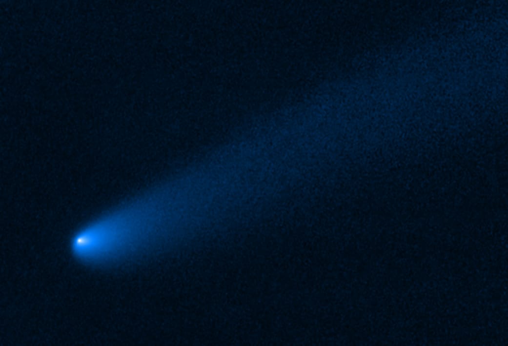 shows a long tail of dust and gas, flowing from the comet's bright solid nucleus in the lower left, toward the upper right.