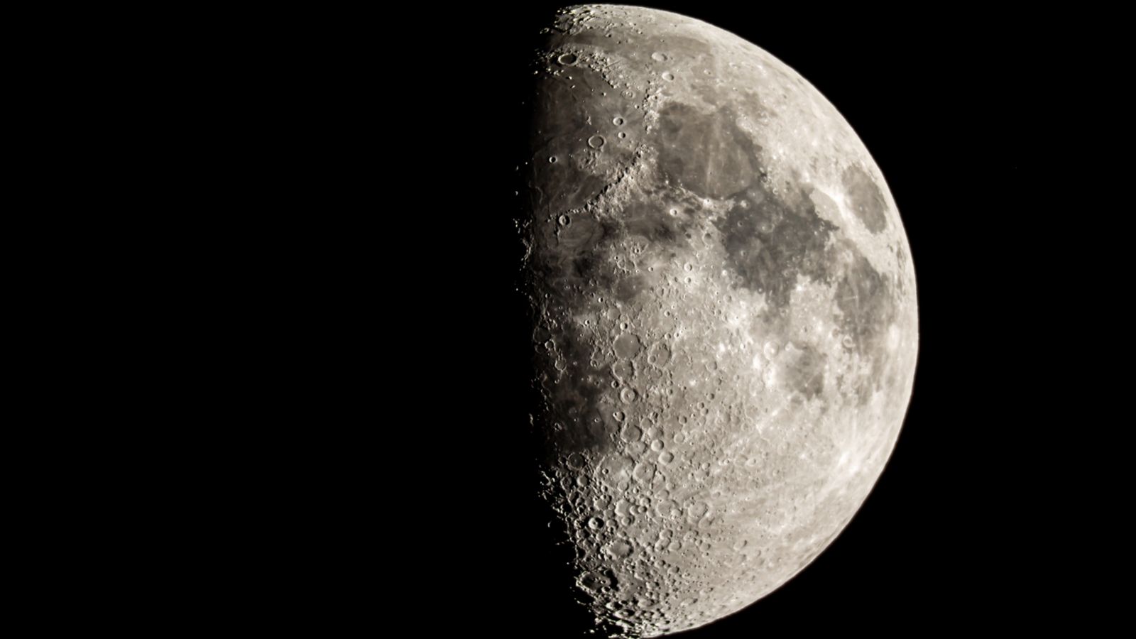 The moon is photographed with its right side lit by sunlight in a black night sky.