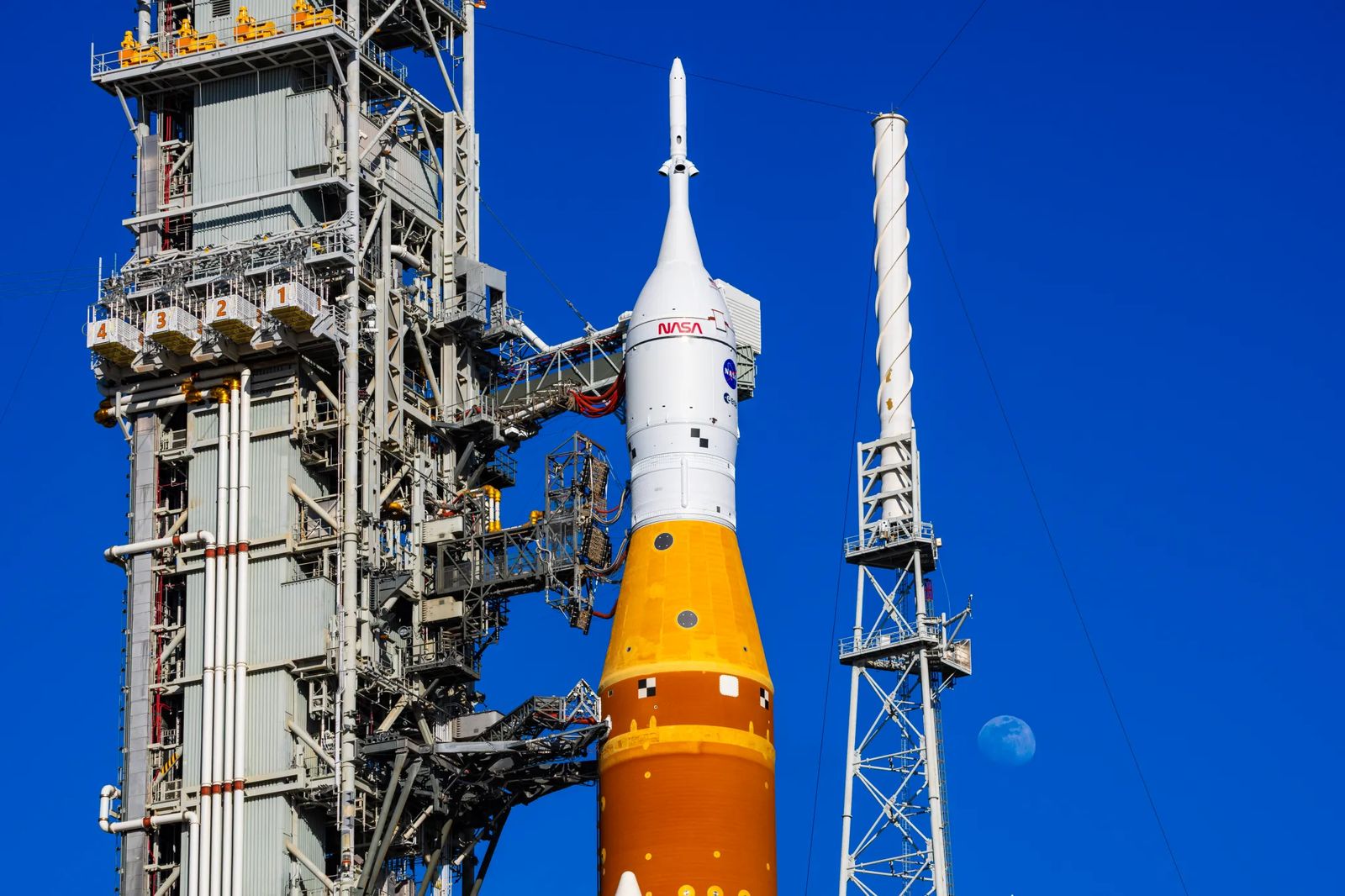 The Moon is seen behind the SLS (Space Launch System) and Orion spacecraft, atop the mobile launcher on January 28, 2026. The rocket is currently at Launch Pad 39B at NASA’s Kennedy Space Center in Florida, as teams are preparing for a wet dress rehearsal to practice timelines and procedures for the launch of Artemis II. 508 Description:The Moon is seen shining over the SLS (Space Launch System) and Orion spacecraft, atop the mobile launcher on January 29, 2026. The rocket is currently at Launch