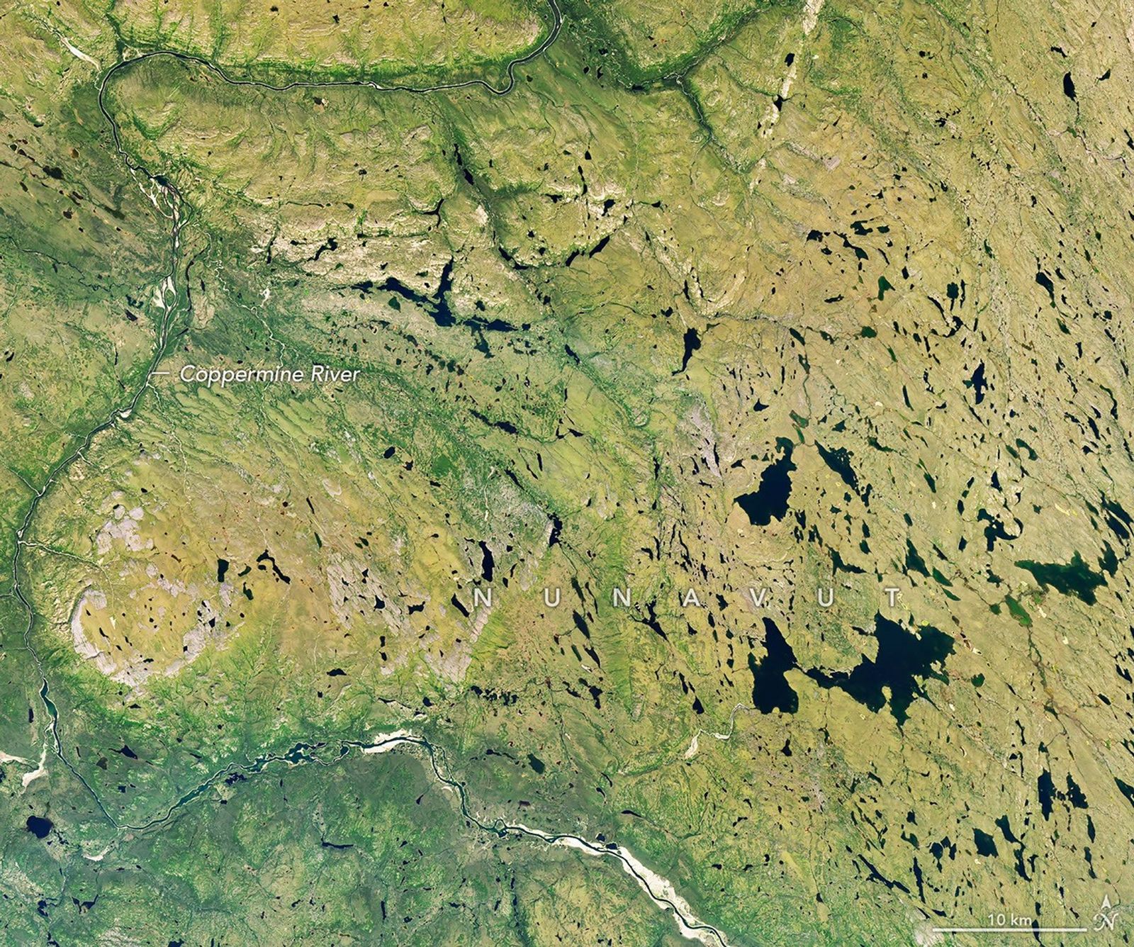 A river winds through a mostly green tundra landscape in summer, dotted with numerous lakes.