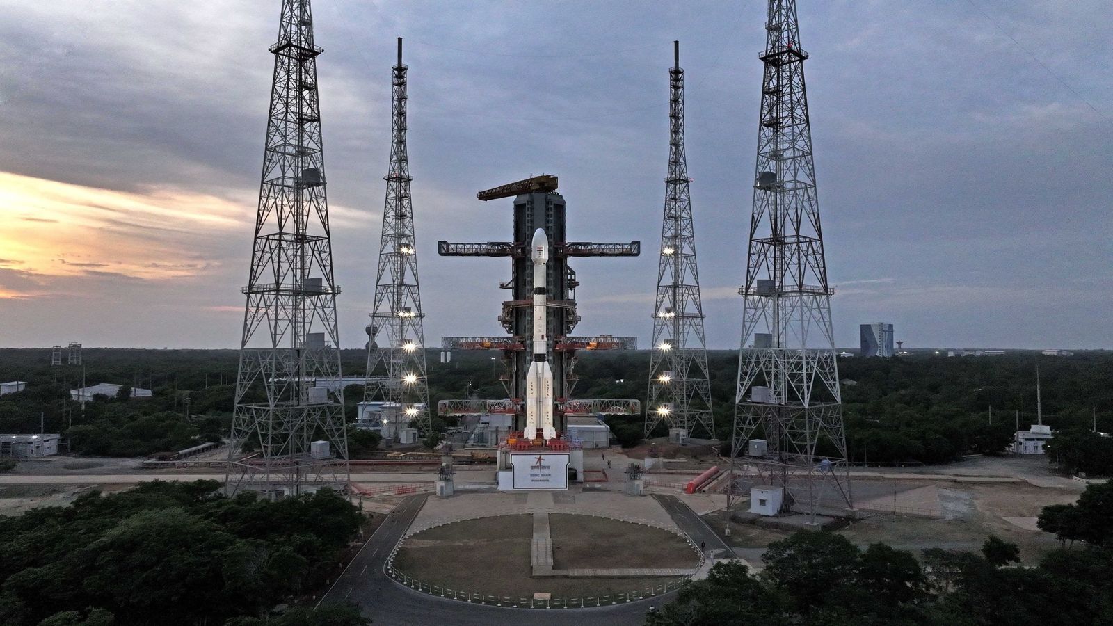 a big white rocket stands on a launch pad beneath a cloudy sky