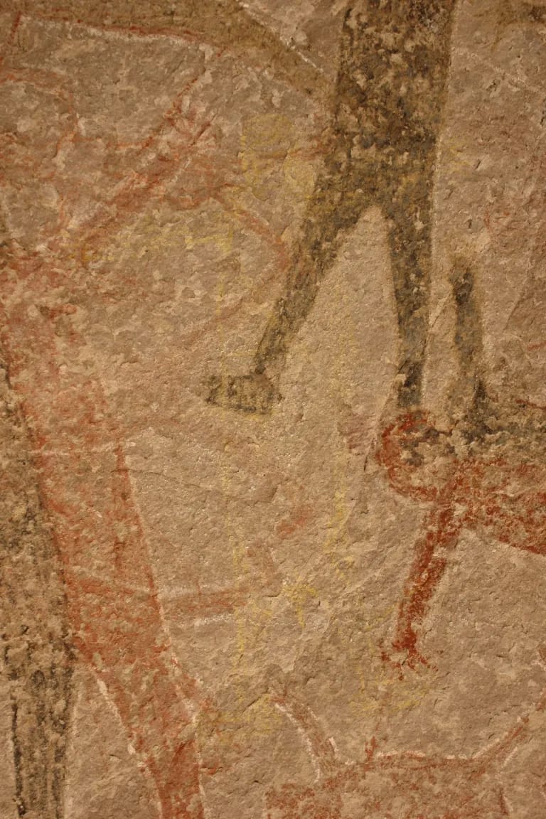 A wall with a series of faded humanoid figures painted on it.
