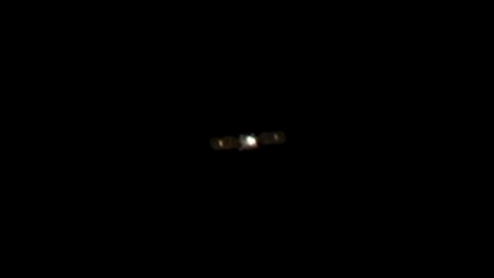 photo of a cube-shaped satellite in deep space, taken from a distance by another satellite