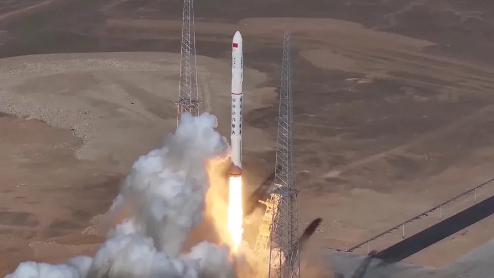 a white rocket launches from a desert pad
