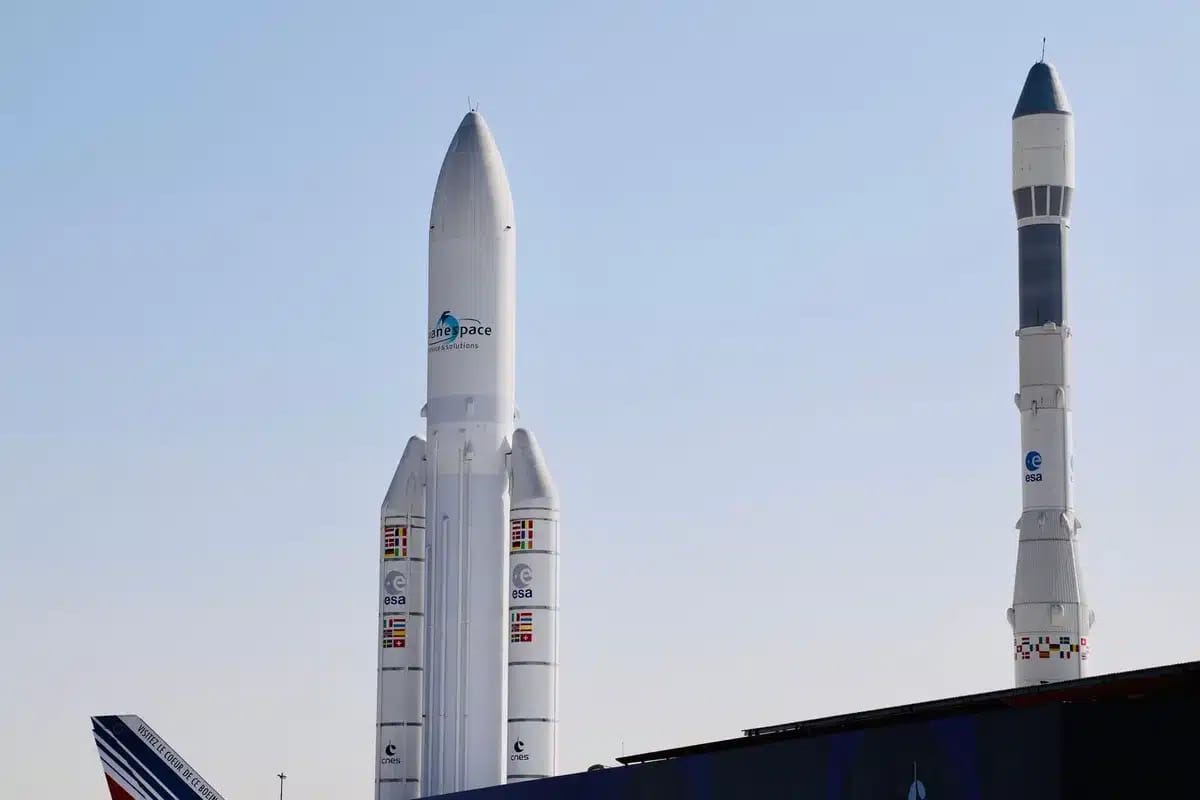 A massive booster standing vertical on a launch pad, all 33 engines glowing white-hot at the base, exhaust plumes billowing outward, the test structure surrounding the rocket backlit by the engine fire, capturing the moment of full-power ignition