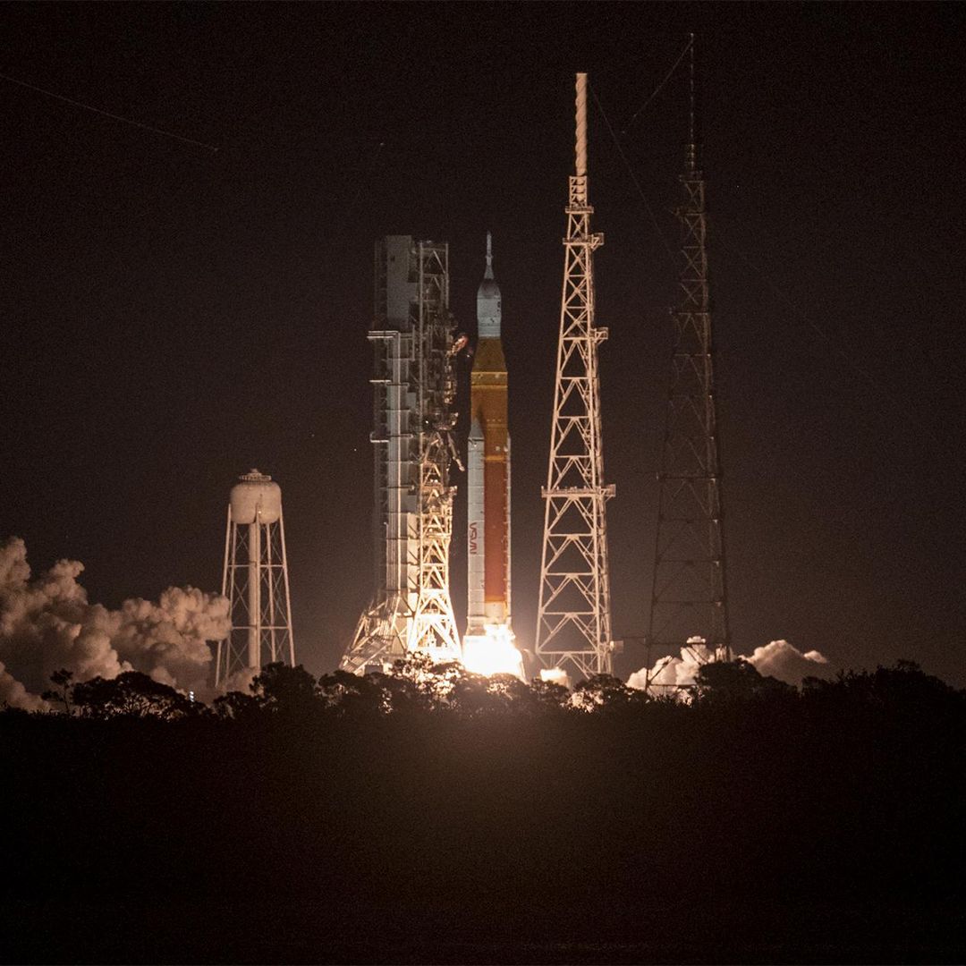 A rocket lifting off the launch pad, just seconds after launch. Fire and plumes of smoke appear at the base of the rocket as it begins to lift off.