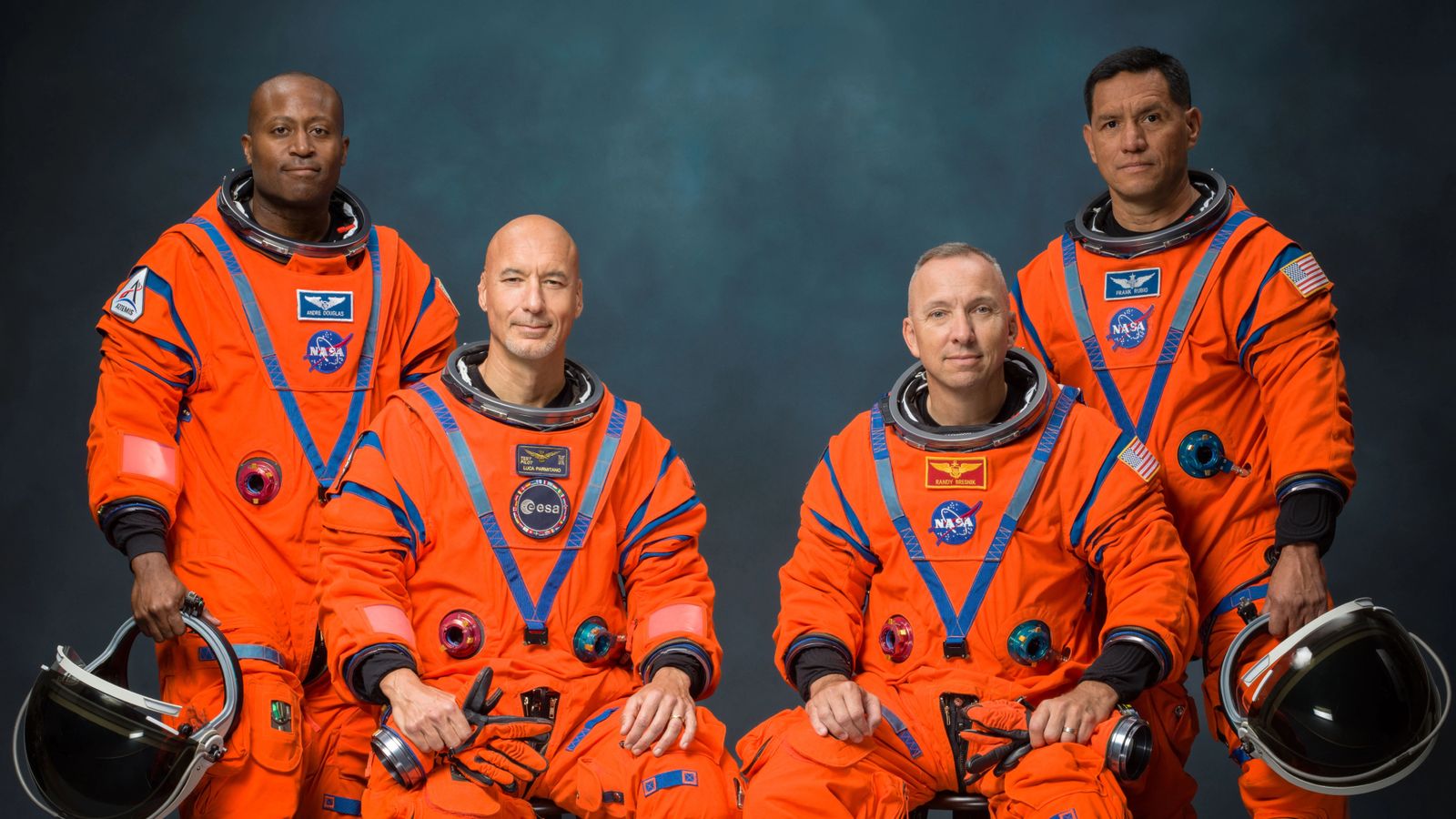 The four male astronauts of NASA's Artemis 3 mission in a portrait wearing their orange spacesuits. They are: Andre Douglas, Luca Parmitano, Randy Bresnick and Frank Rubio.