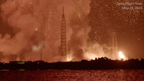 long-distance photo of a fireball and large smoke cloud over a launch pad at night