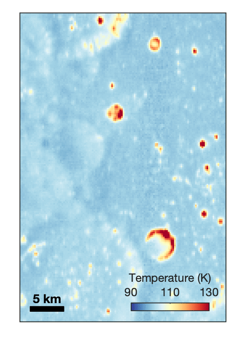Animated temperature map that alternates between two images. A vertical strip through the center blinks on and off, revealing a dark blue circular area surrounding a small white spot near the middle. The pale blue map also contains scattered yellow, orange, and red spots and rings, including a large, curved red-and-yellow feature near the lower center. A 5-kilometer scale bar appears at lower left, and a color key ranges from 90 kelvin in dark blue to 130 kelvin in dark red.
