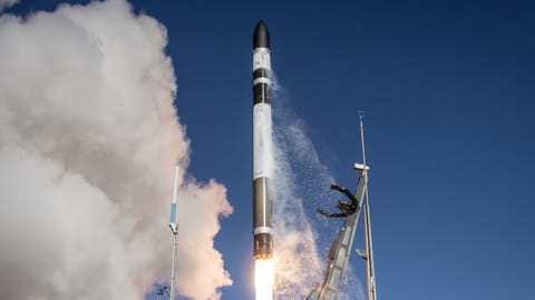 a black and white rocket launches into a blue sky