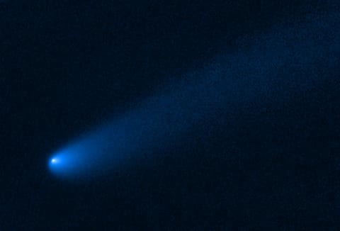 shows a long tail of dust and gas, flowing from the comet's bright solid nucleus in the lower left, toward the upper right.