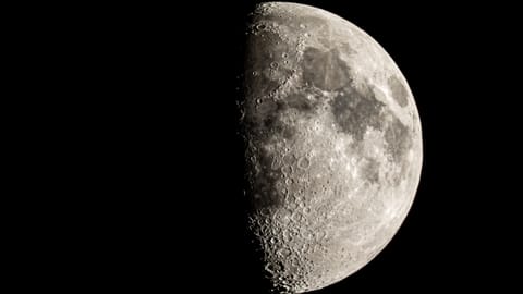 The moon is photographed with its right side lit by sunlight in a black night sky.