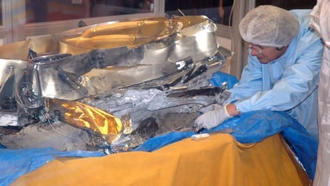 A scientist in protective gear trying to secure solar wind samples from crashed Genesis spacecraft