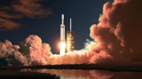A rocket lifts off from a launch pad at dusk.