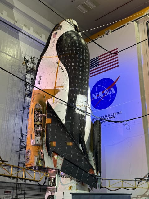 a black and white space plane stands on end in folded up in a hanger.