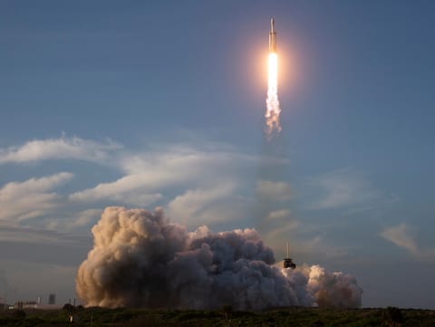 A rocket launches with a plume of smoke.