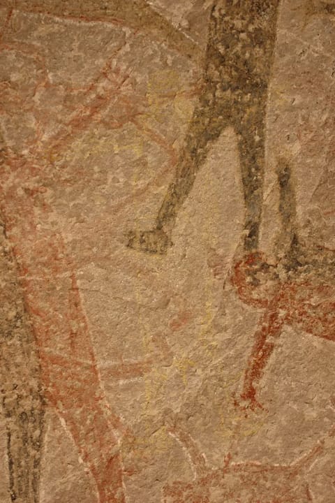A wall with a series of faded humanoid figures painted on it.