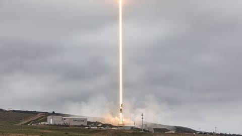 a timelapse exposure of a daytime rocket launch results in a bright beam of light climbing into the overcast sky