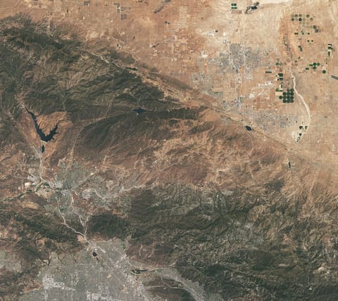 This natural-color image shows the same area, but there is less difference in colors between higher-elevation and lower-elevation vegetation. Most features in the image are shades of brown.