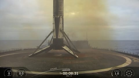 The first stage of a SpaceX Falcon 9 rocket rests on the deck of a ship at sea