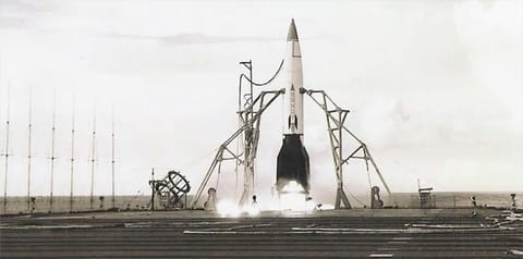 a small rocket with a white body and black fins and nose cone is prepared for launch on the fligh deck of an aircraft carrier