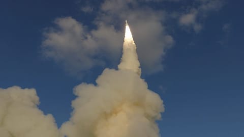 a short, stubby white rocket launches from a ship at sea
