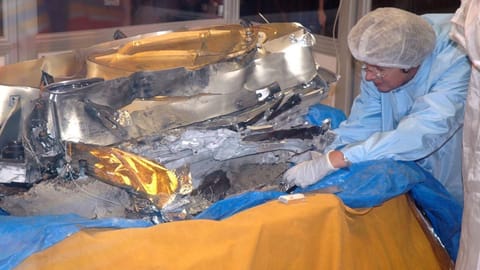 A scientist in protective gear trying to secure solar wind samples from crashed Genesis spacecraft