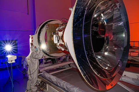 NASA's SPHEREx observatory is oriented in a horizontal position, revealing all three layers of photon shields as well as the telescope. This photo was taken at BAE Systems in Boulder, Colorado, in April 2024.