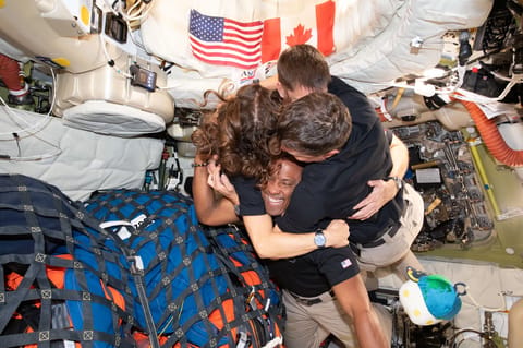 art002e013367 (April 7, 2026) – The Artemis II crew – (clockwise from left) Mission Specialist Christina Koch, Mission Specialist Jeremy Hansen, Commander Reid Wiseman, and Pilot Victor Glover – take time out for a group hug inside the Orion spacecraft on their way home. Following a swing around the far side of the Moon on April 6, 2026, the crew exited the lunar sphere of influence (the point at which the Moon's gravity has a stronger pull on Orion than the Earth's) on April 7, and are headed b