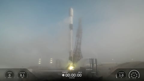 a white rocket upright on a launch pad, partially obscured by fog