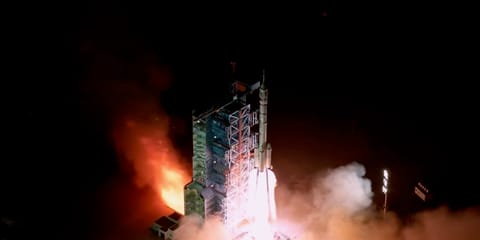 a white rocket launches into a dark night sky