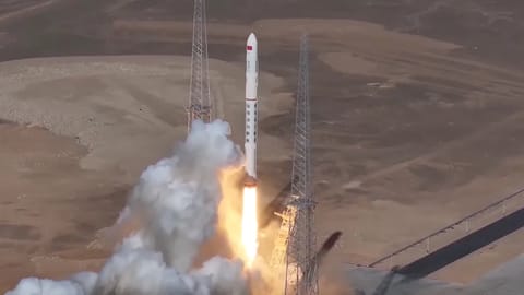 a white rocket launches from a desert pad