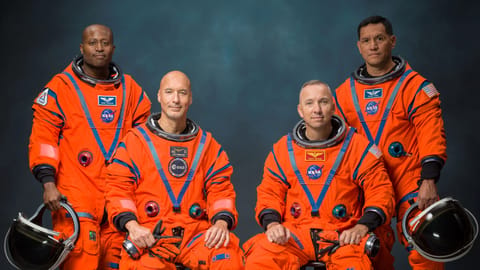The four male astronauts of NASA's Artemis 3 mission in a portrait wearing their orange spacesuits. They are: Andre Douglas, Luca Parmitano, Randy Bresnick and Frank Rubio.