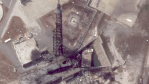 A charred black tower stands over debris after an exposion.