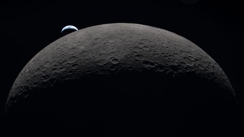 A view of the moon in the foreground with a small Earth in the background.
