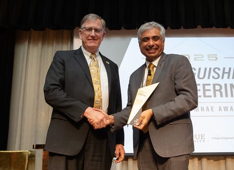 Dan Dumbacher shakes hands with Purdue engineering dean Arvind Raman