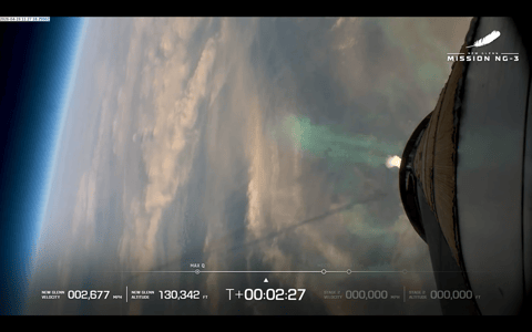 A view of Earth during the launch of Blue Origin's NG-New Glenn rocket as seen from the booster. The shadow of its exhaust plume is visible across the left side of the image.