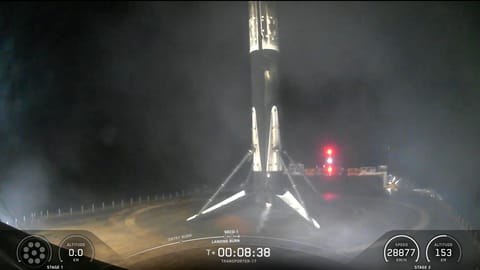 a black and white rocket rests on the deck of a ship at sea at night