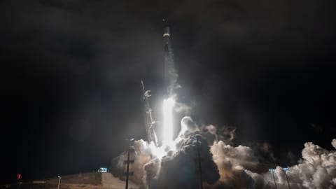a white rocket lifts off above a plume of fire and smoke