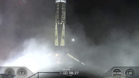 A black and white spacex falcon 9 rocket first stage sits on the deck of a ship at sea.