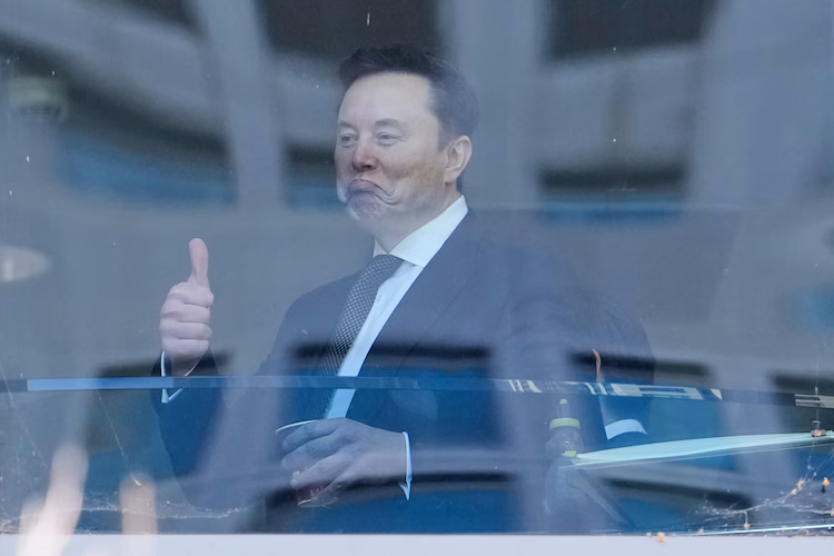 Elon Musk gestures as he walks through a hallway. (Photo: AP)